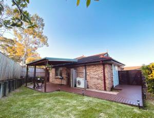 a brick house with a deck in a yard at Cosy 3BR House, 7 mins drive to Macquarie Centre, 5 stars on AirB&B in Sydney