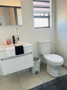 a white bathroom with a toilet and a mirror at Lagoon facing The Blyde in Pretoria