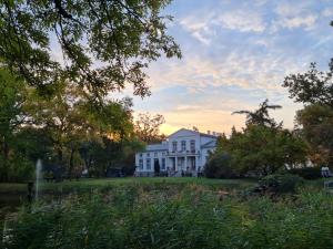 a white house in the middle of a field at Dwór Podstolice - House of Rosenthal in Podstolice