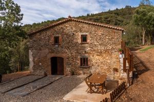 a stone building with a table in front of it at Masia Casa Nova de n'Illa in Montseny
