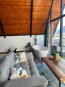 sala de estar con sofá y bañera en Cottage Veranda, en Kazbegi