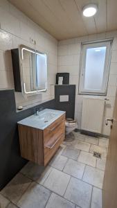 uma casa de banho com um lavatório, um espelho e um WC. em Kleines gemütliches Haus auf dem Land em Linsengericht