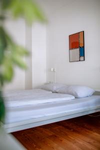 een bed in een witte kamer met een foto aan de muur bij Hostel Multitude in Leipzig