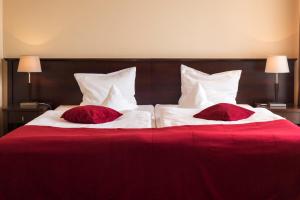 two red and white beds with red pillows on them at Hotel Kudowa Manufaktura Relaksu in Kudowa-Zdrój