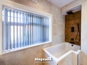 a bathroom with a tub and a large window at Stunning 5bdr Detached King Suite Abode in Leicester