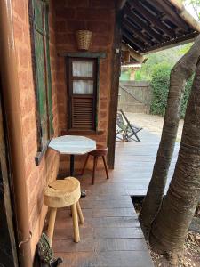 eine Terrasse mit einer Bank, einem Tisch und einem Stuhl in der Unterkunft Abrigo Cipó in Serra do Cipo