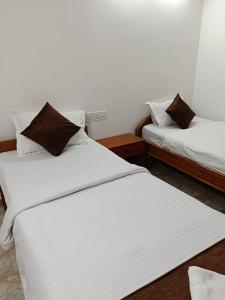 two beds in a room with white sheets and brown pillows at HOTEL ATITHI GRAND in Guwahati