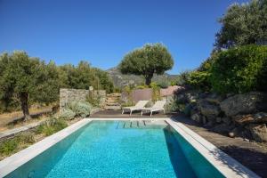 a swimming pool with two chairs next to a rock wall at VILLA MATELIA in Neos Marmaras