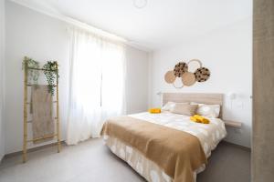 1 dormitorio blanco con 1 cama grande con almohadas amarillas en Venegas Urban Suites By Bevacacional, en Las Palmas de Gran Canaria