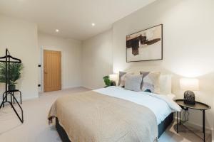 Luxurious & Modern London Apartment in Honor Oak في لندن: غرفة نوم بسرير كبير وبجدران بيضاء