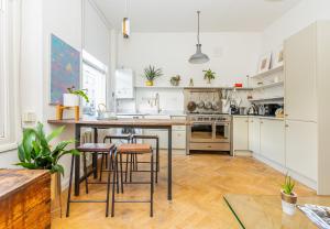 a kitchen with white cabinets and bar stools at Stunning 2BR Apt wPatio in Dalston, 2 min to Tube in London