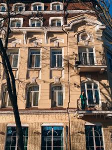 un homme debout sur un balcon en face d'un bâtiment dans l'établissement Alexandrovskiy Hotel, à Odessa