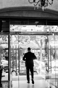 a man in a suit walking through a glass door at Alexandrovskiy Hotel in Odesa
