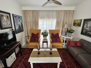a living room with a couch and two chairs at Somerset West Garden Apartments 2 in Somerset West