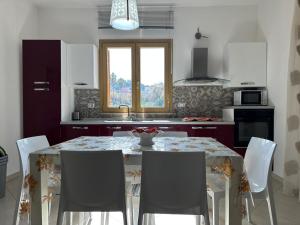 een keuken met een tafel met stoelen en een raam bij Mare Blu Apartament in Balestrate