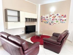 een woonkamer met twee leren stoelen en een televisie bij Mare Blu Apartament in Balestrate