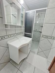 y baño blanco con lavabo y ducha. en Pousada Santa Barbara en Florianópolis