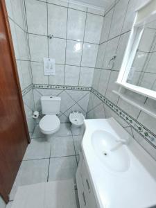 a white bathroom with a toilet and a sink at Pousada Santa Barbara in Florianópolis