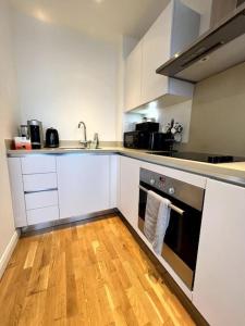 eine Küche mit weißen Schränken und Holzböden in der Unterkunft Beautiful 1 Bed Flat close to Clapham Trendy in London
