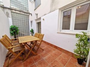 een patio met een houten tafel en stoelen op een balkon bij CDZ - San Telmo, apartamentos con terraza in Cádiz