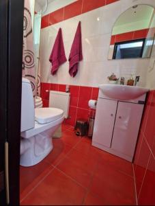 a red and white bathroom with a toilet and a sink at CozyPlace in Kuldīga