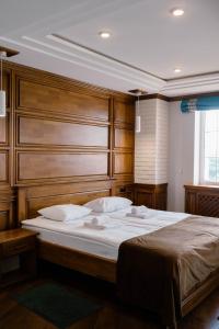 Schlafzimmer mit einem großen Bett mit einem Kopfteil aus Holz in der Unterkunft Taras Bulba in Kamjanez-Podilskyj