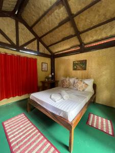 1 dormitorio con 1 cama grande y cortina roja en Concepcion Divers Lodge en Busuanga
