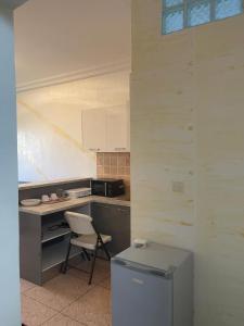 uma cozinha com uma cadeira, uma mesa e um frigorífico em Studio meuble sacre cœur em Dakar