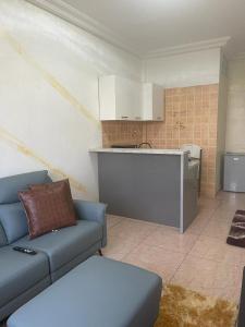 a living room with a blue couch and a kitchen at Studio meuble sacre cœur in Dakar