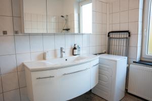 een witte badkamer met een wastafel en een spiegel bij Volante Apartment Bremen-Findorff in Bremen