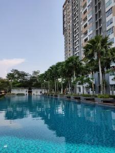 une grande piscine avec des palmiers et des bâtiments dans l'établissement Warm and cozy apartment@JB, à Johor Bahru