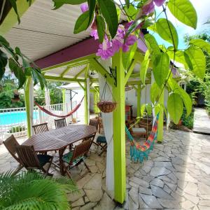 a patio with a wooden table and chairs and a tree at Logisrev in Sainte-Anne