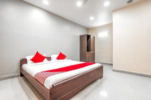 een slaapkamer met een groot bed met rode kussens bij OYO Flagship Sathya Inn in Warangal