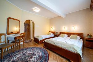 una camera d'albergo con due letti e uno specchio di Lilla Panzió a Odorheiu Secuiesc