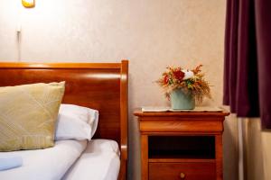 a bedroom with a bed and a table with a vase of flowers at Lilla Panzió in Odorheiu Secuiesc