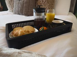 a tray of food with bread and orange juice on a bed at Station House Haworth in Haworth