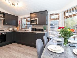 a kitchen with black cabinets and a table with flowers at Ruskin Lodge in Windermere