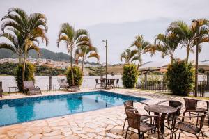 een zwembad met stoelen, tafels en palmbomen bij Hotel Novo Horizonte - By UP Hotel in Monte Sião