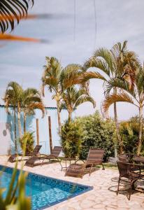 een zwembad met stoelen en palmbomen naast de oceaan bij Hotel Novo Horizonte - By UP Hotel in Monte Sião