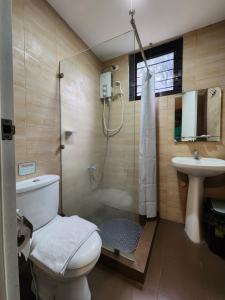 a bathroom with a shower and a toilet and a sink at Grayhouse Inn Tagaytay in Tagaytay