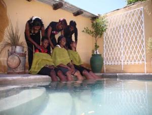 a group of people sitting next to a swimming pool at Die Tuishuise & Victoria Manor in Cradock