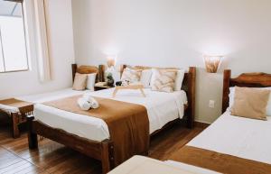 Duas camas num quarto com paredes brancas e pisos em madeira em Hotel Novo Horizonte - By UP Hotel em Monte Sião