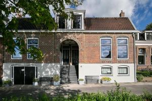 ein Backsteinhaus mit einer weißen Tür und einer Treppe in der Unterkunft Molepôlle 7 - Stadslogementen Franeker in Franeker