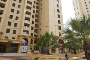 a large building with palm trees in front of it at Shams JBR Hostel in Dubai