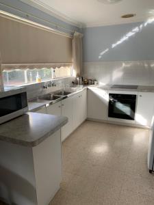 a white kitchen with white cabinets and appliances at Hamersley Hacienda in Perth