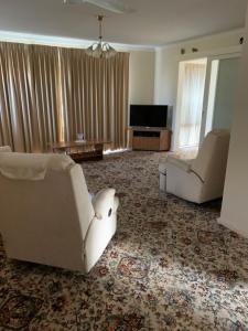 Sala de estar con 2 sofás blancos y TV en Hamersley Hacienda en Perth