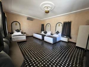 a room with two beds with black and white checkered floors at Riad Akabar Merzouga in Merzouga +35 photos