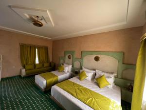 a hotel room with two beds and a couch at Riad Akabar Merzouga in Merzouga