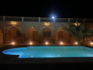 a swimming pool in a courtyard at night at Riad Akabar Merzouga in Merzouga