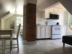 a kitchen with white cabinets and a brick pillar at ATELIER DU CLOCHER Studio #5 in Kamouraska